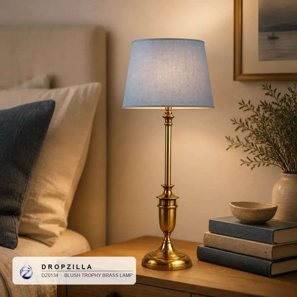 A blush trophy brass lamp glowing on a bedside